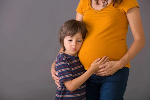 Criança, menino, abraçando sua mãe grávida em casa, isolado — Fotografia de Stock