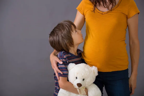 Маленька дитина, хлопчик, обіймаючи вагітну матір вдома, ізольована — стокове фото