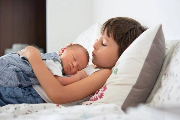 Hermoso niño, abrazando con ternura y cuidar a su bebé recién nacido — Foto de Stock