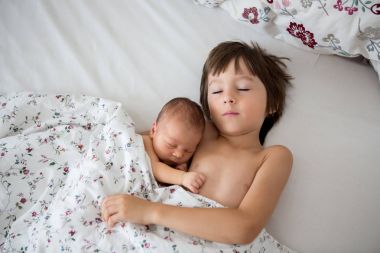 Güzel çocuk, hassasiyet ile sarılma ve onun yeni doğan Bebek Bakımı