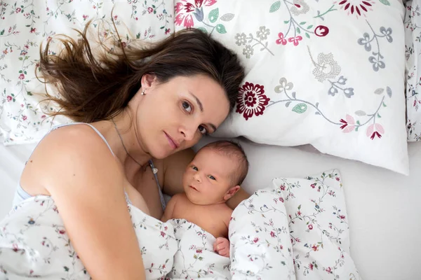 Jovem mãe deitada na cama com seu bebê recém-nascido — Fotografia de Stock