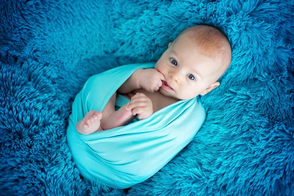 Słodkie trzy miesiące baby boy w niebieski wrap, leżącego na niebieski bla — Zdjęcie stockowe