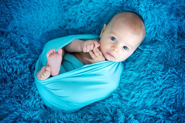 Cute three months old baby boy in blue wrap, lying on a blue bla — Stock Photo, Image