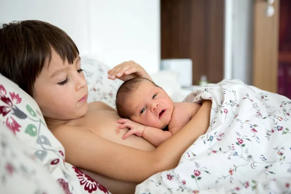 Красивий хлопчик, обіймається ніжністю і доглядає за новонародженою дитиною — стокове фото