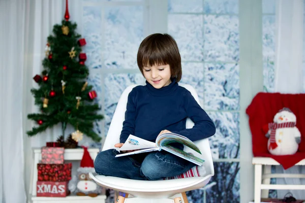 Cute child, boy, reading a book, sitting on a chair — Stock Photo, Image