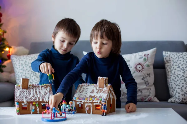 Dois filhos, irmãos meninos, brincando com casas de gengibre — Fotografia de Stock