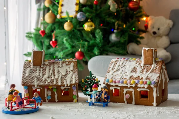 Two gingerbread houses, tree and people sitting on a bench