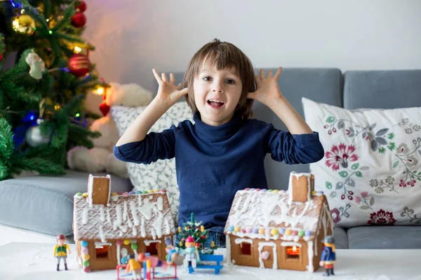 Criança bonito, menino, brincando com casas de gengibre — Fotografia de Stock