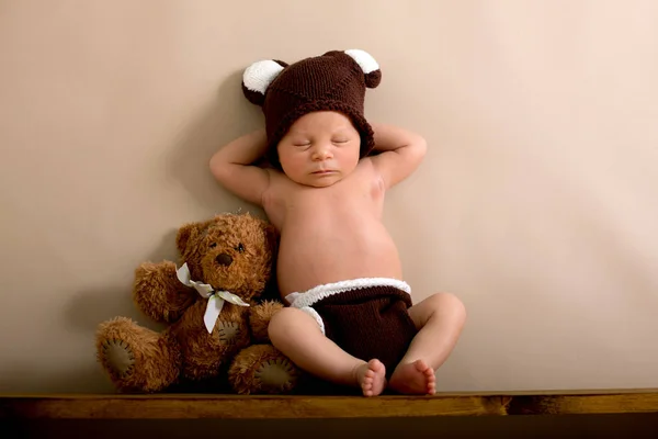 Nyfödd pojke klädd i en brun stickad Björn mössa och byxor, sle — Stockfoto