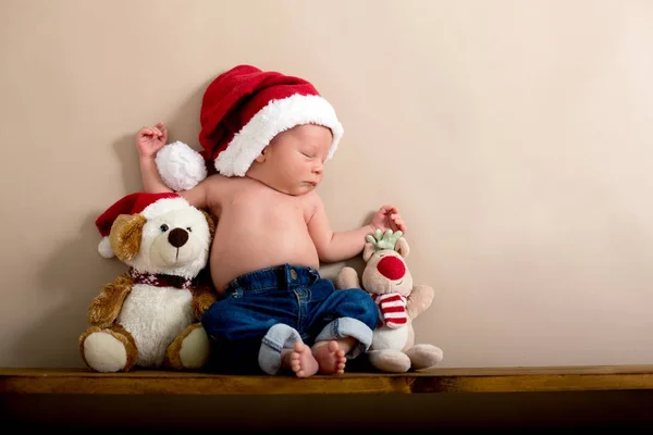 生まれたばかりの赤ちゃん男の子クリスマス帽子とジーンズを身に着けているで寝ています。 — ストック写真