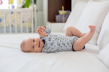 Sevimli küçük yeni doğan bebek çocuk yatakta sabah oynarken,