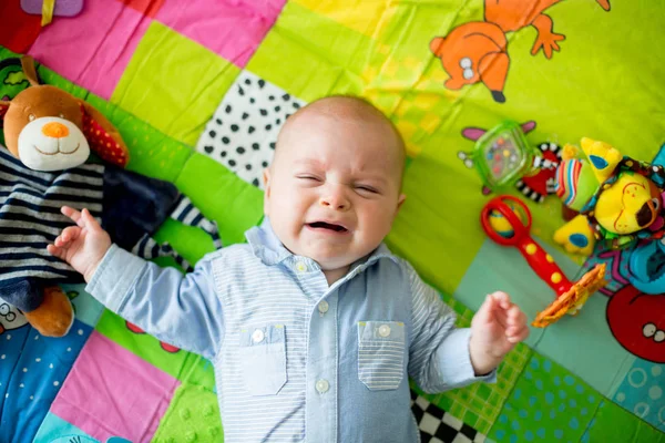 Three months old baby boy, crying at home on a colorful activity — Stock Photo, Image