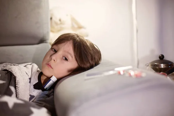 Sick child boy lying on the sofa with a fever — Stock Photo, Image