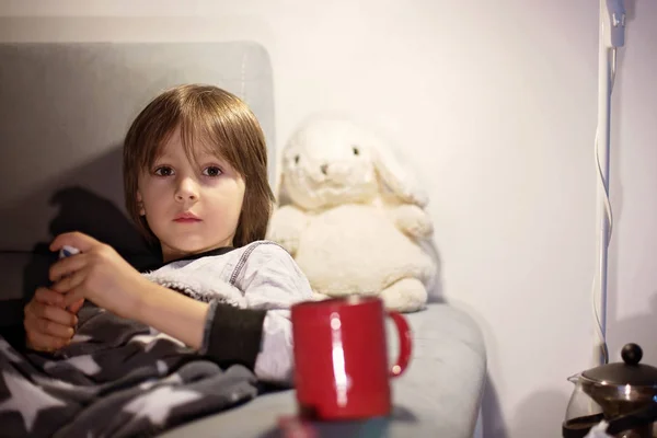 Sick child boy lying on the sofa with a fever — Stock Photo, Image