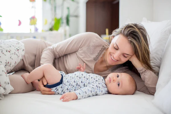 Fiatal anya, ágyban neki újszülött fiú játék — Stock Fotó