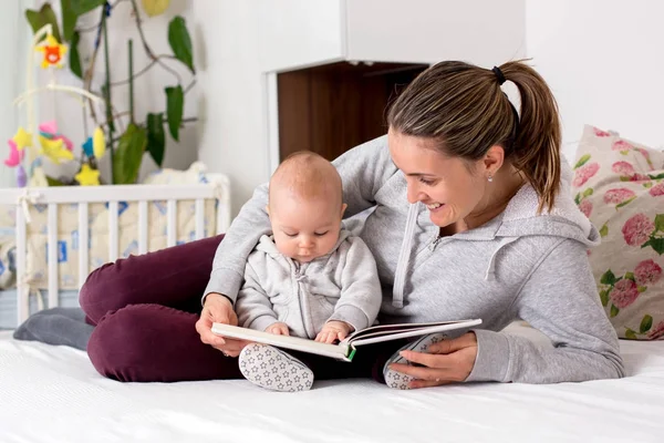 Jovem mãe, lendo um livro para seu menino, mostrando-lhe foto — Fotografia de Stock