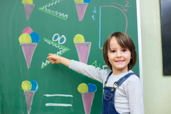 Menino do primeiro ano na escola, mostrando números e calculando — Fotografia de Stock