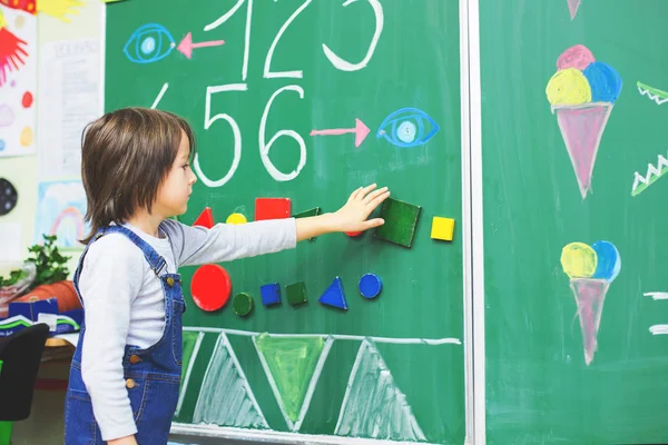 Junge der ersten Klasse in der Schule, Zahlen zeigen und rechnen — Stockfoto