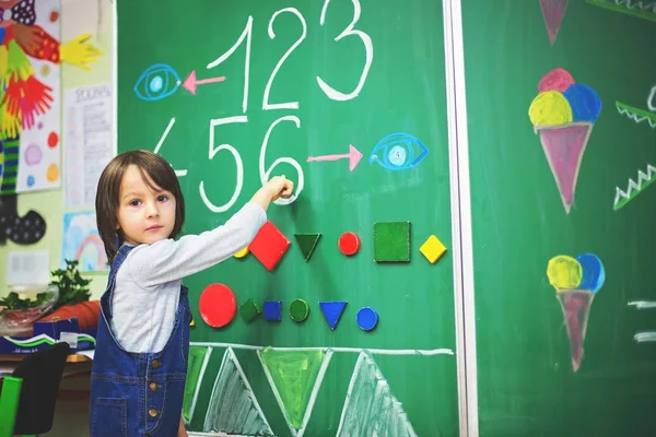 Junge der ersten Klasse in der Schule, Zahlen zeigen und rechnen — Stockfoto