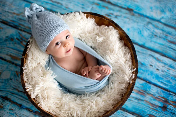 Маленький мальчик в вязаной шляпе в корзине, счастливо улыбающийся — стоковое фото