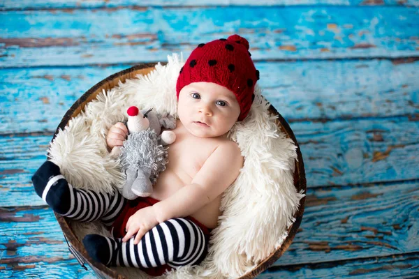 Маленький хлопчик з в'язаним капелюхом у кошику, щасливо посміхається — стокове фото