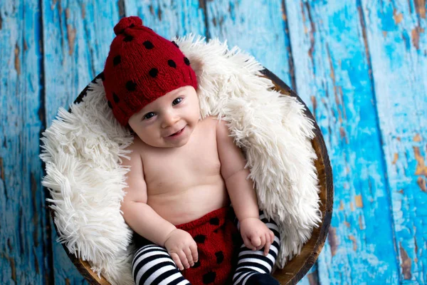 Kleiner Junge mit Strickmütze im Korb, glücklich lächelnd — Stockfoto