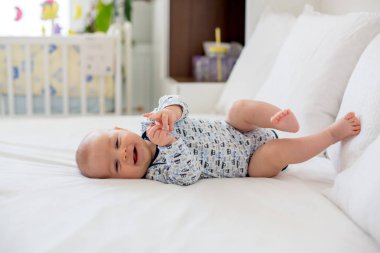 Sevimli küçük yeni doğan bebek çocuk yatakta sabah oynarken,