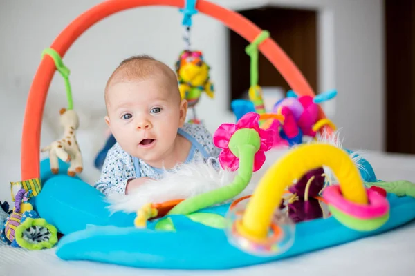 Lindo bebé en el gimnasio colorido, jugando con juguetes colgantes en casa — Foto de Stock
