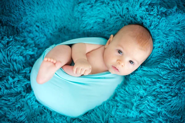 Cute three months old baby boy in blue wrap, lying on a blue bla — Stock Photo, Image