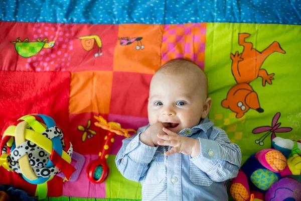 Glad tre månader gammal pojke, spelar hemma på en färgglad en — Stockfoto
