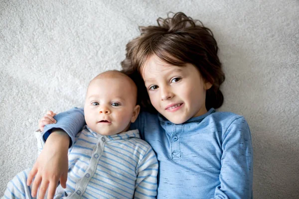 Frères heureux, bébé et enfants d'âge préscolaire, embrasser à la maison sur — Photo