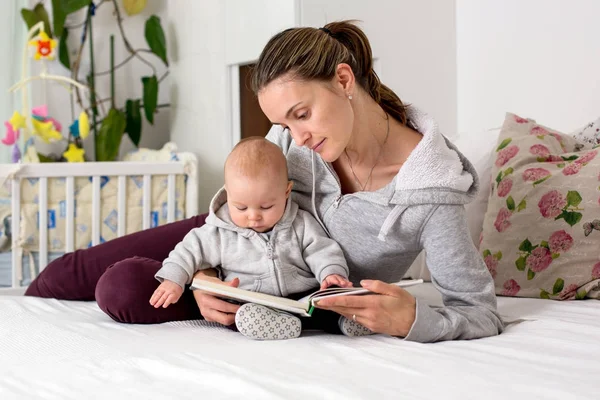Młoda matka, czytając książkę na jej synka, pokazując mu pictur — Zdjęcie stockowe