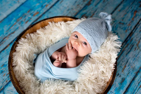 Kleiner Junge mit Strickmütze im Korb, glücklich lächelnd — Stockfoto