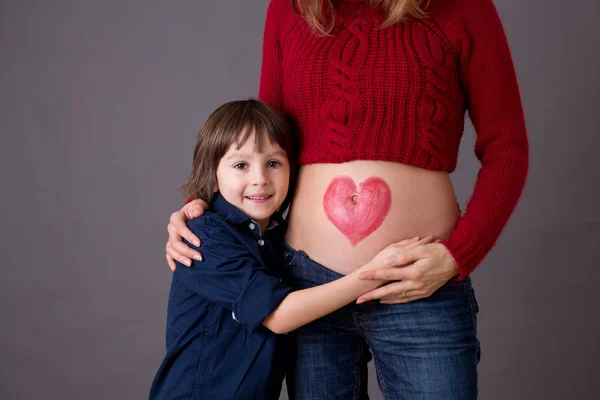 Hermoso niño preescolar, abrazando a su madre embarazada —  Fotos de Stock