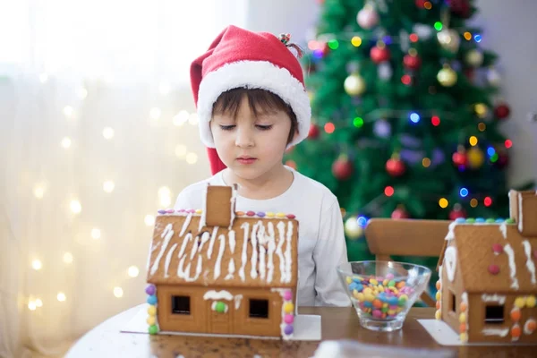 Niedlicher kleiner Junge, der Lebkuchenhaus für Weihnachten backt — Stockfoto