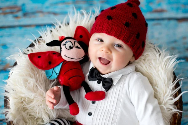 Niño pequeño con sombrero de mariquita de punto y pantalones en una cesta —  Fotos de Stock