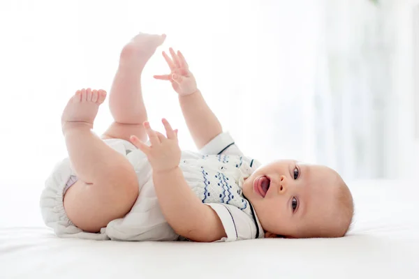 Cute little four month old baby boy, playing at home in bed — Stock Photo, Image