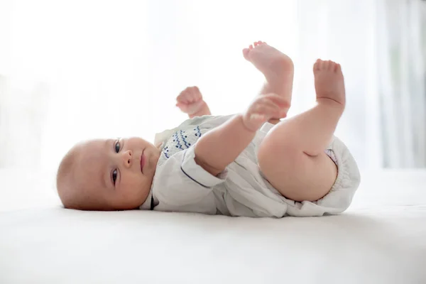 Cute little four month old baby boy, playing at home in bed — Stock Photo, Image