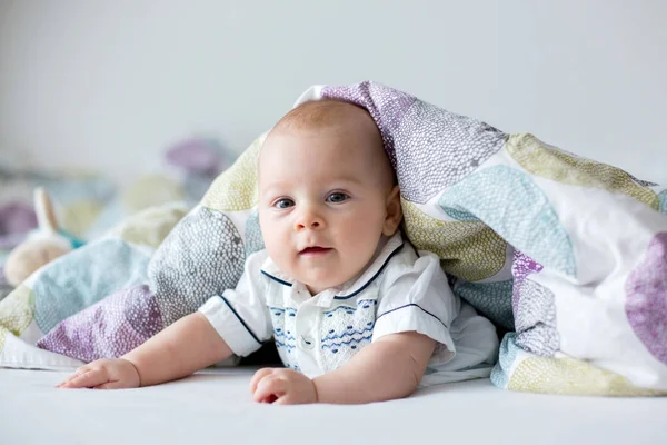 Cute little four month old baby boy, playing at home in bed — Stock Photo, Image