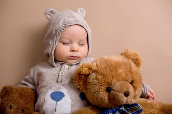 Słodkie baby boy w ponosi ogólną, spanie na półce z teddy b — Zdjęcie stockowe