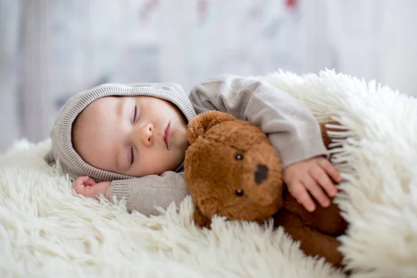 Sweet baby boy in bear overall, sleeping in bed with teddy bear — Stock Photo, Image