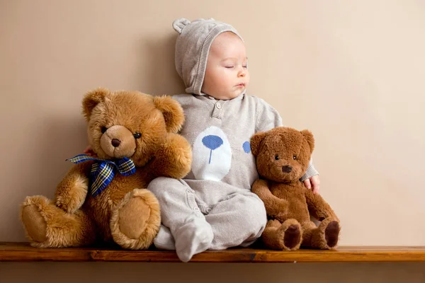 Sweet baby boy in bear overall, sleeping on a shelf with teddy b — Stock Photo, Image