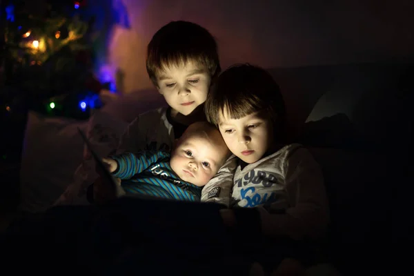 Drei Brüder, die zu Hause auf dem Sofa im Wohnzimmer sitzen und lesen — Stockfoto