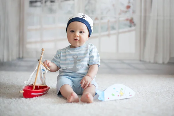 Lille dreng, leger wtih lille båd og lille fisk på hom - Stock-foto