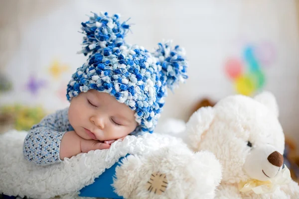 Menino com chapéu de malha, dormindo com ursinho de pelúcia bonito — Fotografia de Stock