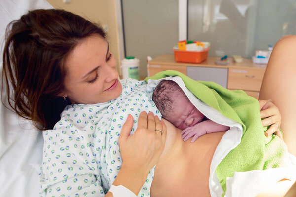 Happy mom, having her baby skin to skin first seconds after birt