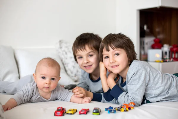 3 人の子供、赤ん坊、朝ベッドで彼のより古い兄弟 — ストック写真