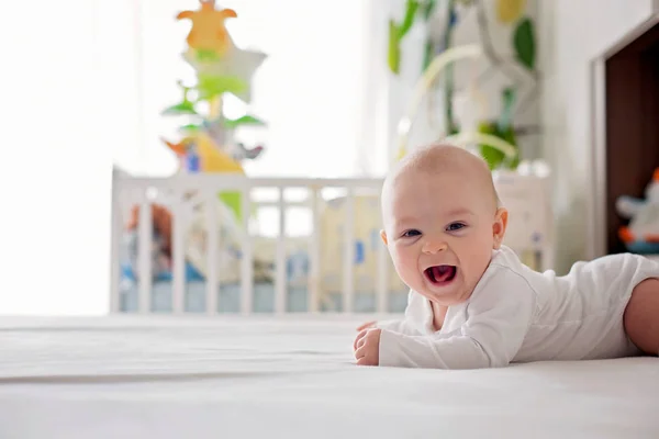 Cute little four month old baby boy, playing at home in bed in b — Stock Photo, Image