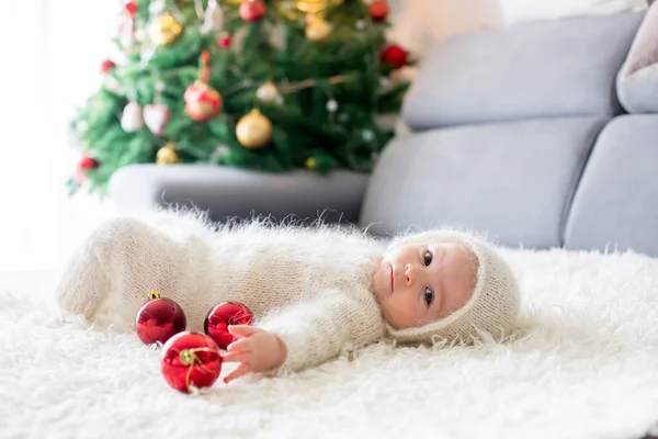 Liten pojke i vit stickad onesie, leka med och bibehålls — Stockfoto