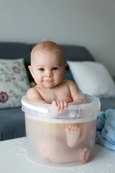 Aranyos kis négy hónapos kisfiát, játszik a vödör tele — Stock Fotó